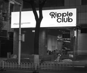 Nighttime street view of Ripple Club cafe with large illuminated sign, exposed brick facade, and scooters parked in front.