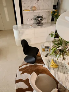 Modern breakfast nook featuring a curved Calacatta marble table, a sculptural black organic chair, a cowhide rug, and a built-in marble coffee station with espresso machine.