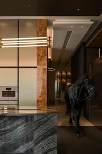 Modern luxury kitchen with dark marble island, warm burl wood panel, linear pendant light, and a realistic black horse sculpture in the hallway.