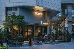 台中怪獸咖啡店傍晚景色，擁有茂盛的戶外庭園座位區、木製家具、盆栽植物，以及在溫暖燈光下放鬆的顧客。