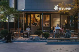 台北怪物咖啡店傍晚外觀，設有戶外木質座椅、碎石花園、大型岩石，顧客在溫暖燈光下享用飲品。