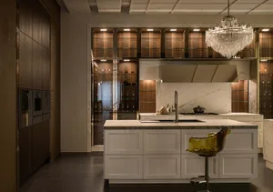 Modern luxury kitchen featuring a large white marble island, integrated sink, amber translucent bar stool, dark wood cabinetry, and a sparkling crystal chandelier.