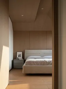 View into a minimalist bedroom featuring a beige upholstered bed, wood-paneled walls and ceiling, and a grey floating nightstand with framed art.