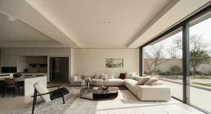Modern open-plan living room featuring a large L-shaped bouclé sofa, irregular marble coffee table, black leather and bouclé armchair, and expansive glass doors opening to a garden.