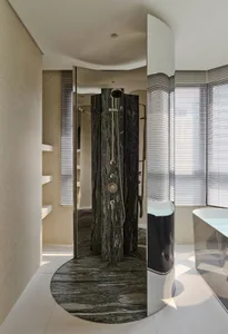 Modern luxury bathroom with a curved dark green marble shower room and freestanding white bathtub next to a large window with blinds.