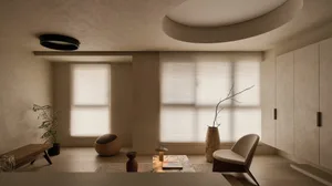 Minimalist living room featuring micro-cement walls, a curved ceiling detail, low wooden lounge chair, marble coffee table, and large windows with sheer blinds.