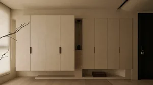 Modern minimalist entryway featuring full-height beige micro-cement cabinetry with floating bench and open niche displaying a Buddha head sculpture.