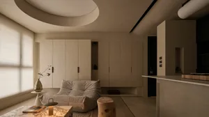 Modern minimalist living room featuring a Togo-style modular sofa, micro-cement walls and ceiling with a large circular recessed light, marble coffee table, and natural wood elements.