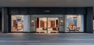 Night view of the modern luxury shoe store Pane with large glass windows, terrazzo stone columns, wooden display fixtures, and warm interior lighting.
