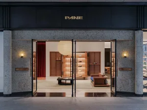 Front entrance view of PANE shoe store featuring large terrazzo pillars, black metal-framed glass doors, wooden display shelves with integrated lighting, and a large white paper lantern pendant.
