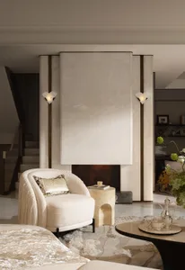 Modern luxury living room featuring a large travertine marble fireplace wall, cream boucle armchair with patterned pillow, travertine side table, and layered neutral rugs.