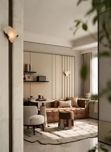 Modern luxury living room featuring a brown tufted leather sofa, cream boucle armchair, marble side table, and geometric area rug in neutral tones.