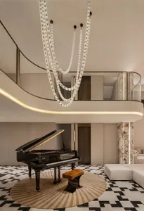 Modern double-height living room with black grand piano on a circular beige and brown striped rug, dramatic crystal chain chandeliers, black and white geometric marble floor, and curved second-floor balcony with marble pillars.
