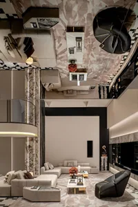Luxurious double-height living room with beige modular sofas, black leather accent chair with gold piping, large camouflage-patterned area rug, marble coffee tables, and dramatic mirrored ceiling reflecting the space below.