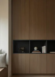 Modern walnut wood built-in wall unit featuring closed cabinets below and open black-lined niches above, displaying a bronze bull sculpture, stacked books, and a textured ceramic vase.