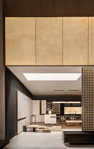 Modern luxury open-plan living and dining area featuring a large backlit travertine marble wall, dark textured accent wall, wooden ceiling, and minimalist furniture under a skylight.