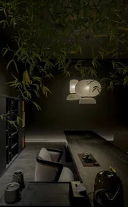 Modern Japanese-style tea room featuring a long dark wood table, light fabric armchairs, hanging paper lanterns, and fresh bamboo foliage hanging from the ceiling.