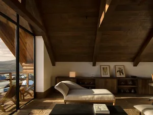 Modern rustic living room with high reclaimed wood beamed ceiling, sculptural beige chaise lounge, dark coffee table, and large glass doors opening to a mountain balcony.