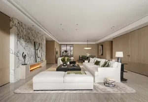 Modern luxury living room featuring a large white marble accent wall with fireplace, white L-shaped sofa, large white ottoman, and light wood cabinetry.