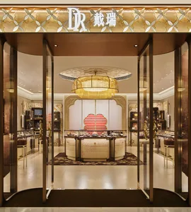 Luxurious jewelry store interior with a large golden woven lantern chandelier, curved cream display counters, ornate wall panels, and glass entrance doors.