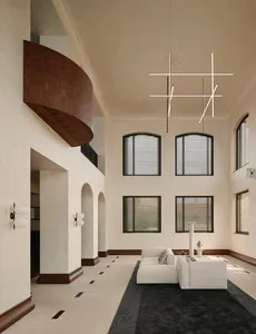 Spacious double-height living room featuring a curved walnut balcony, white L-shaped sectional sofa on a dark rug, modern geometric chandelier, and arched doorways with dark wood trim.