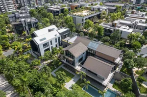 Aerial view of modern luxury villas featuring silver and dark metal cladding, large glass windows, rooftop terraces, private swimming pools, and surrounded by dense tropical greenery in a high-end residential community.