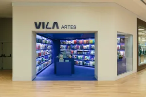 Entrance view of Vila Artes bookstore featuring vibrant blue LED-lit bookshelves, blue carpet, and a central blue display island.