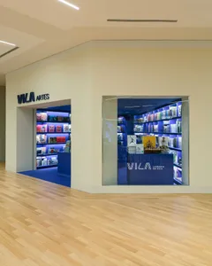Modern bookstore interior with intense blue LED lighting, floating bookshelves, and a glass display window set within a light wood and off-white retail corridor.