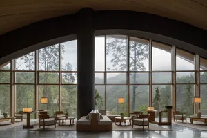 Modern luxury lounge with curved wooden ceiling, oak furniture and large panoramic windows overlooking misty green mountains