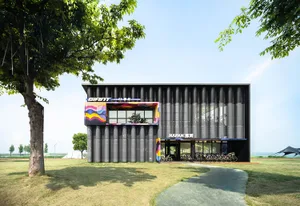 Modern black corrugated metal bicycle hub building with colorful graphic panels and numerous bicycles parked under the canopy on a sunny day.