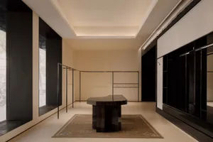 Modern minimalist entryway featuring a large ebony marble console table on a vintage Persian rug, with black architectural details and warm neutral walls.