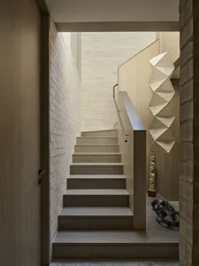 Modern minimalist wooden staircase with light oak treads, white painted brick walls, stainless steel handrail, and a large geometric white paper pendant light hanging beside it.