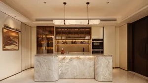 Modern luxury home bar with a large curved Calacatta marble island, ribbed texture detail, integrated lighting, and matching alabaster pendant lights hanging above.