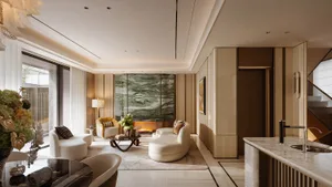 Modern luxury living room with a striking green marble feature wall, curved white sofas, marble kitchen island, and warm ambient lighting.