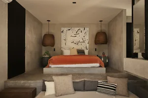 Modern minimalist bedroom featuring a raised concrete platform bed with orange throw blanket, two large woven rattan pendant lamps, black and white abstract painting, and built-in concrete seating with neutral cushions.