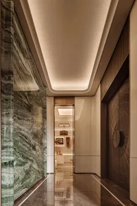 Modern luxury hallway with green marble wall, dark marble floor, recessed ceiling lighting, and a view into a walk-in closet.