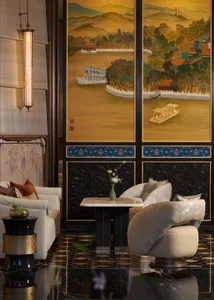 Luxurious modern Chinese-style lounge with a large golden landscape painting screen, white curved sofa, patterned swivel chair, and glossy black marble floor.