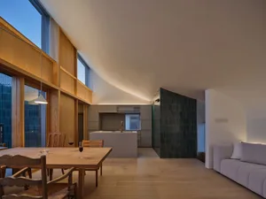 現代開放式餐廳，木製拱形天花板、淺木色餐桌椅、混凝土中島廚房，以及深綠色磁磚 accent 牆，搭配弧形天花設計。