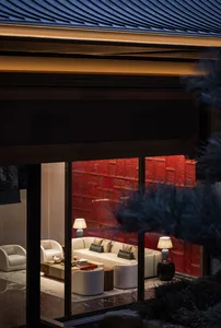 透過玻璃門欣賞奢華當代中式客廳，戲劇性的紅漆雕花牆面、米白沙發與優雅燈光交織。