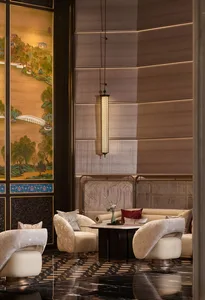 Luxurious Chinese-style lounge featuring cream velvet swivel armchairs, dark marble floor with gold inlay, traditional landscape screen, and elegant pendant lighting.