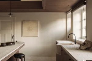 Modern minimalist kitchen featuring a curved travertine island and countertop, dark wood cabinetry, black leather stool, and large window with natural sunlight.