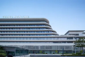 Exterior view of the Grand Mercure hotel featuring a modern curved, multi-layered white facade with extensive glass windows under a clear blue sky.