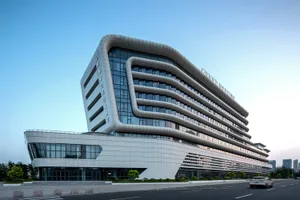 Exterior view of the Grand Intercontinental Hotel in Taichung, Taiwan, showcasing its distinctive curved white facade and extensive glass windows under a clear blue sky.