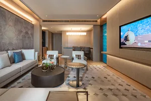Modern luxury living room with light wood herringbone wall panels, a large blue television feature wall, a circular dark wood coffee table, and a geometric patterned area rug.