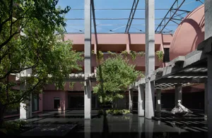 粗獷主義建築的下沉式中庭，擁有巨型混凝土柱、粉紅色牆面、黑色反射水池、綠樹，以及晴空下的巨大粉紅色圓頂。