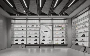 Modern monochrome retail store interior with extensive metal shelving displaying various athletic shoes, categorized by sport type under bright linear ceiling lights.