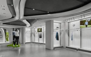 Modern golf apparel store interior with flowing sculptural ceiling, concrete walls, metal clothing racks, and green interactive display platforms.