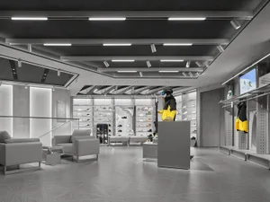 Modern minimalist ski and snowboard retail store interior featuring concrete walls, geometric floor tiles, linear LED lighting, grey lounge seating, and a mannequin wearing a bright yellow and black ski jacket.