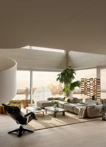 Modern luxury living room with large floor-to-ceiling windows showing a harbor city skyline at sunset, featuring a black leather lounge chair, neutral sectional sofa, beige area rug, and sculptural elements.