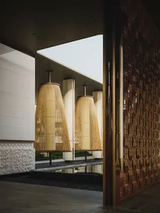 Modern luxury entrance hall with two large woven bamboo pendant lamps hanging over a shallow reflecting pool, next to a textured white stone wall and a dark brown woven metallic wall panel.